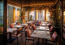 18th Floor Rooftop Restaurant to Open at The Gantry, Stratford Rooftop dining terrace at sunset with tables set for dinner, pink cushions and floral installations