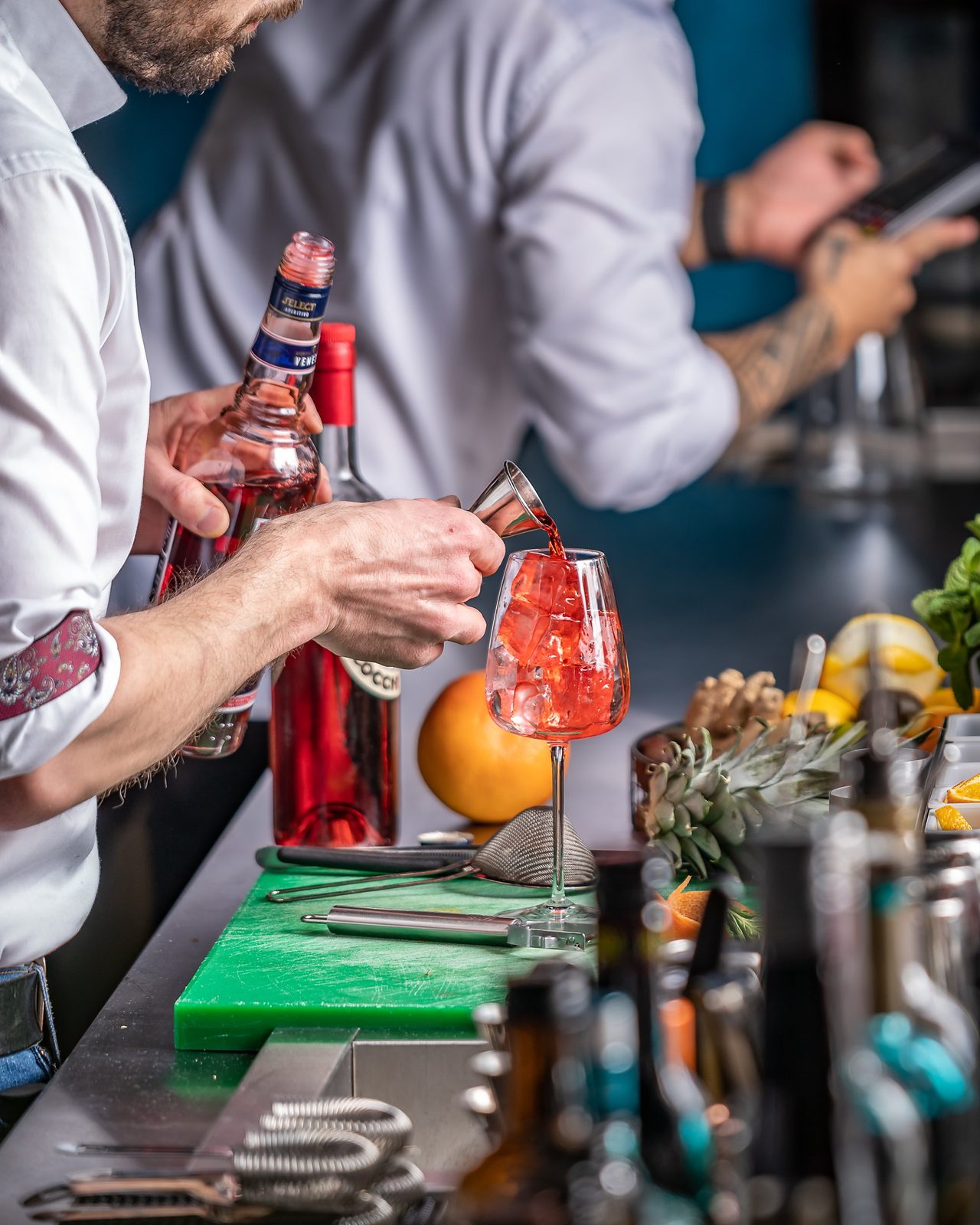 Bartender pouring a red aperitivo into an ice-filled wine glass at the bar