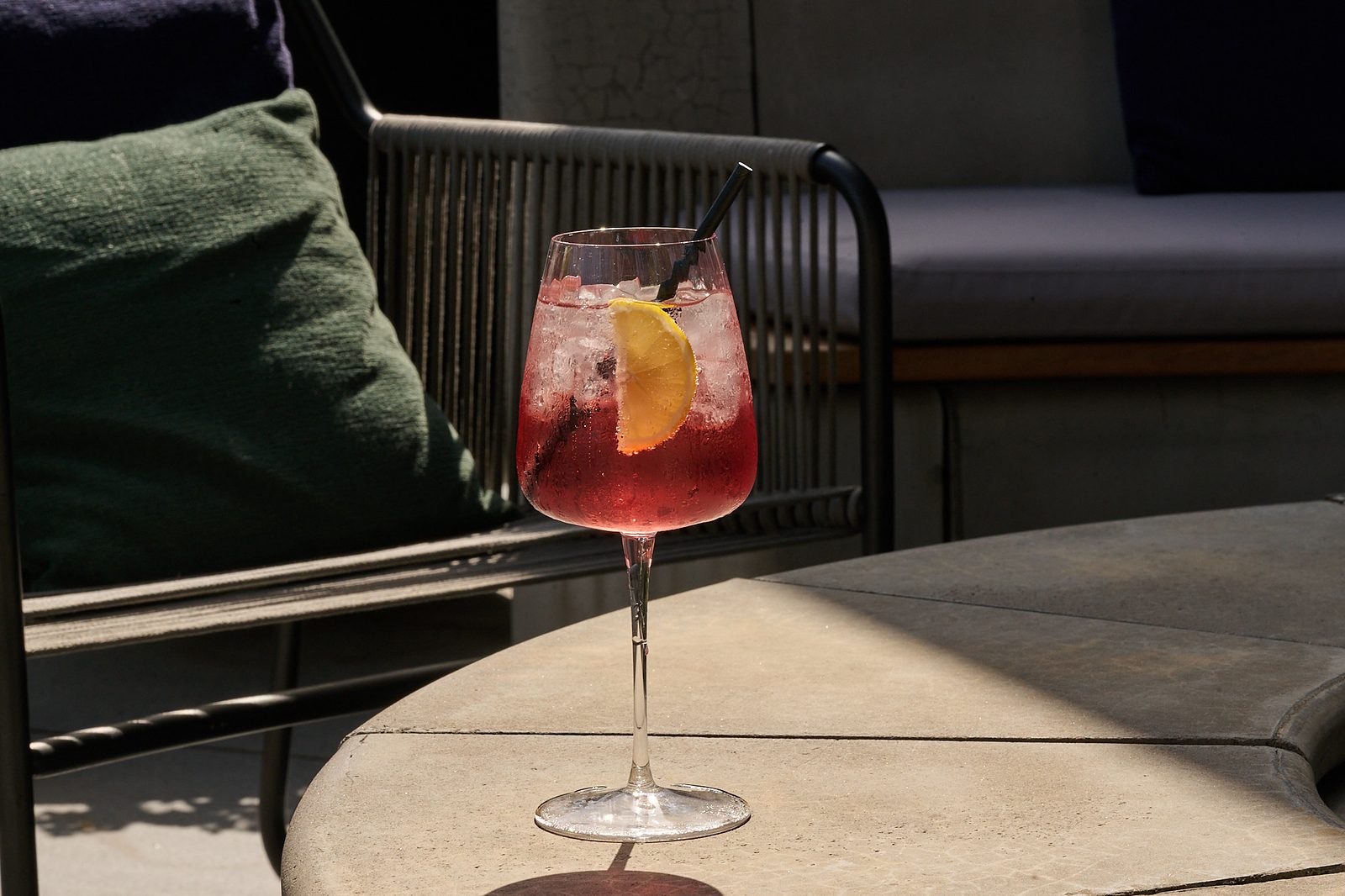 Red spritz with a lemon slice on an outdoor table