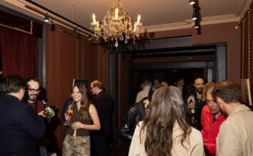 Guests in a red-walled room with a crystal chandelier at Adelphi Art House