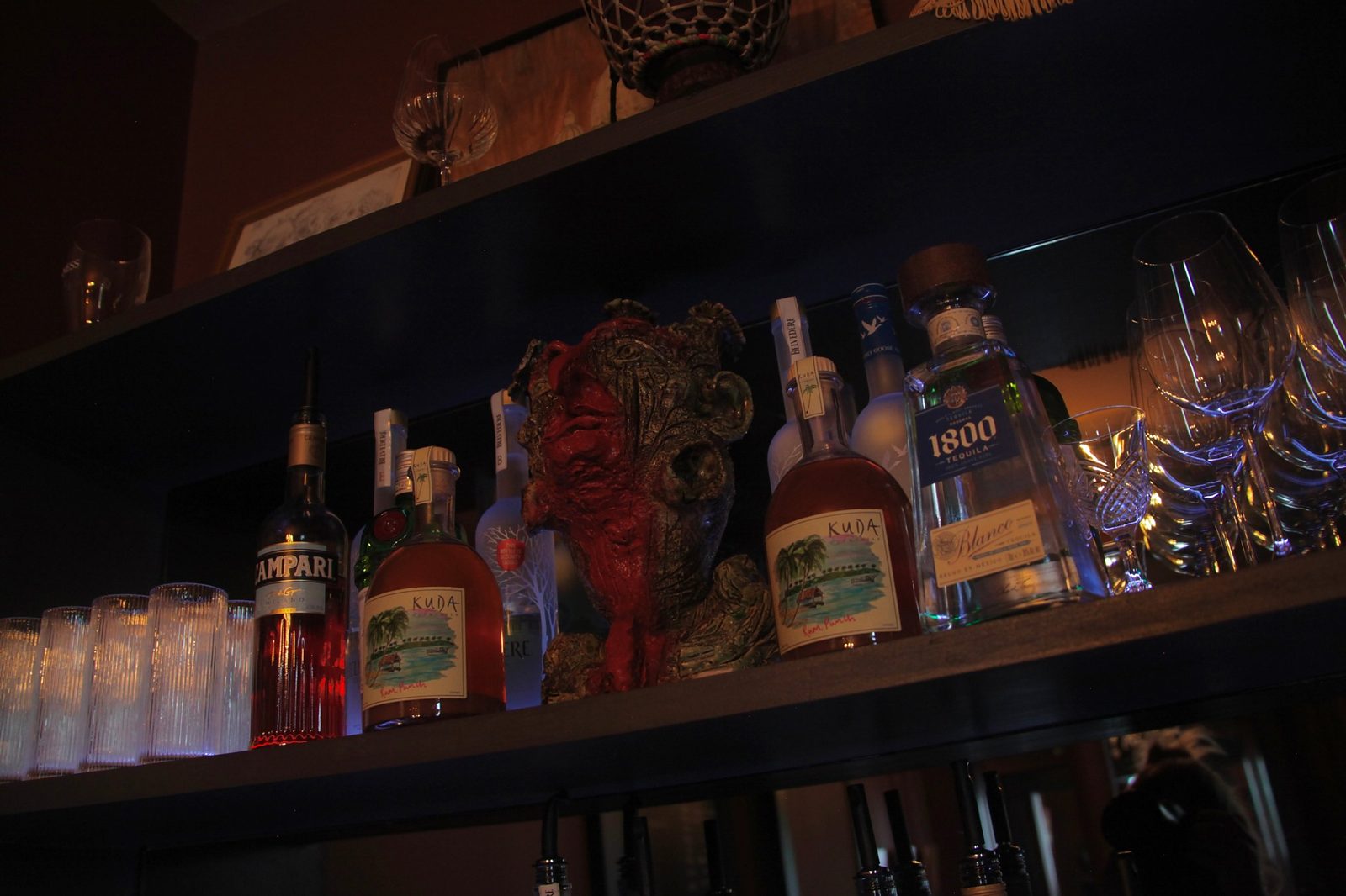 Back bar shelves with spirits, glassware and a sculpted head at Adelphi Art House