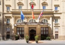Facade of Grand Hotel et des Palmes in Palermo, with flags above the canopied entrance