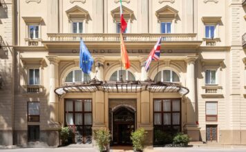 Facade of Grand Hotel et des Palmes in Palermo, with flags above the canopied entrance