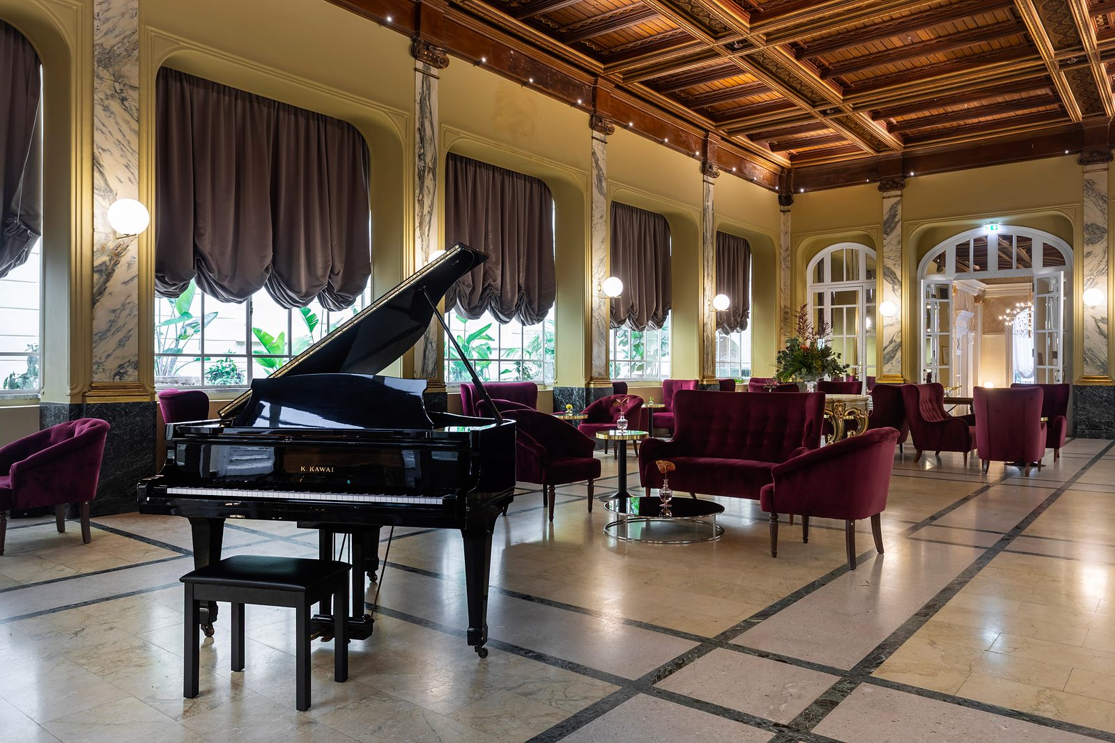 Winter Garden at Grand Hotel et des Palmes, with a grand piano, velvet armchairs and a coffered wooden ceiling