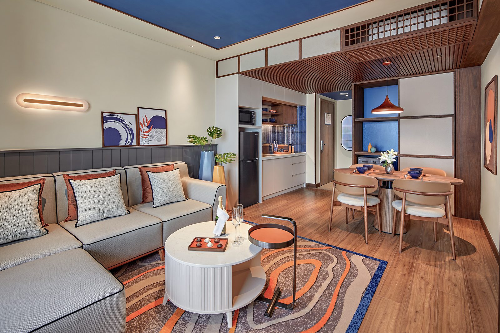 Two-bedroom serviced apartment living and dining area at LÈGACY Hanoi, with wooden tones and indigo accents