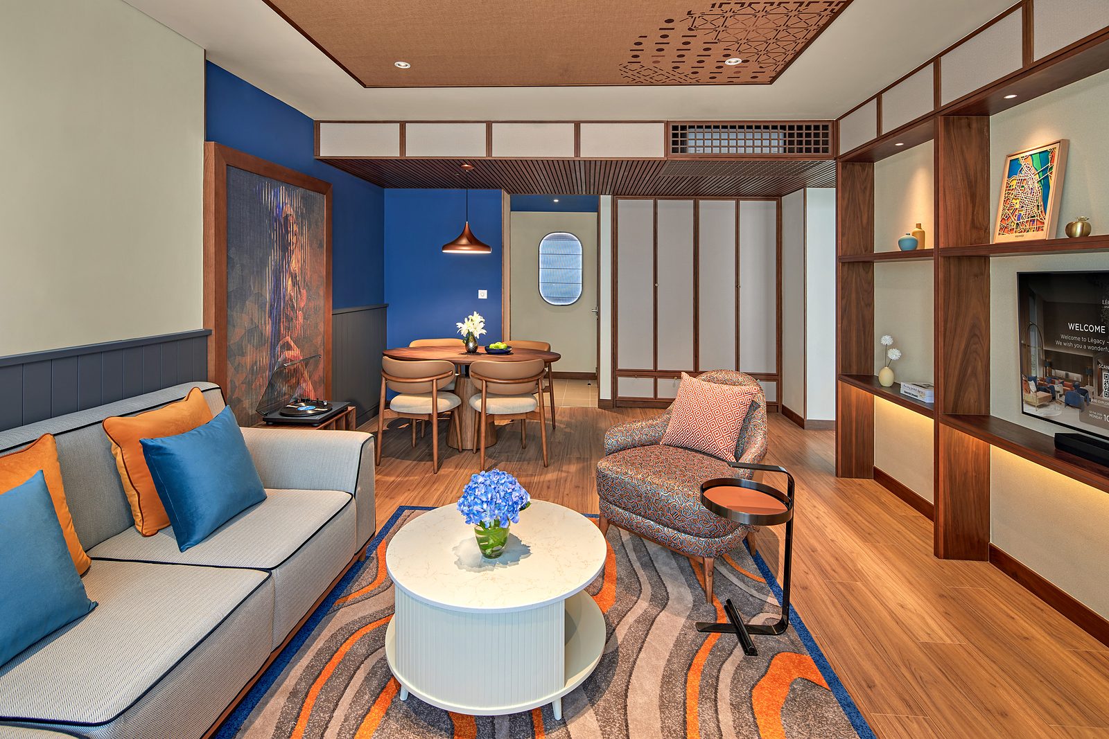 Deluxe Suite living area at LÈGACY Hanoi, with a sofa, dining table and patterned rug