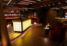The Vinyl Room at NinetyNine Regent Street, with a glowing glass-block bar, red velvet seating and record sleeves on the walls