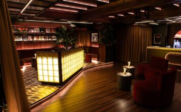 The Vinyl Room at NinetyNine Regent Street, with a glowing glass-block bar, red velvet seating and record sleeves on the walls