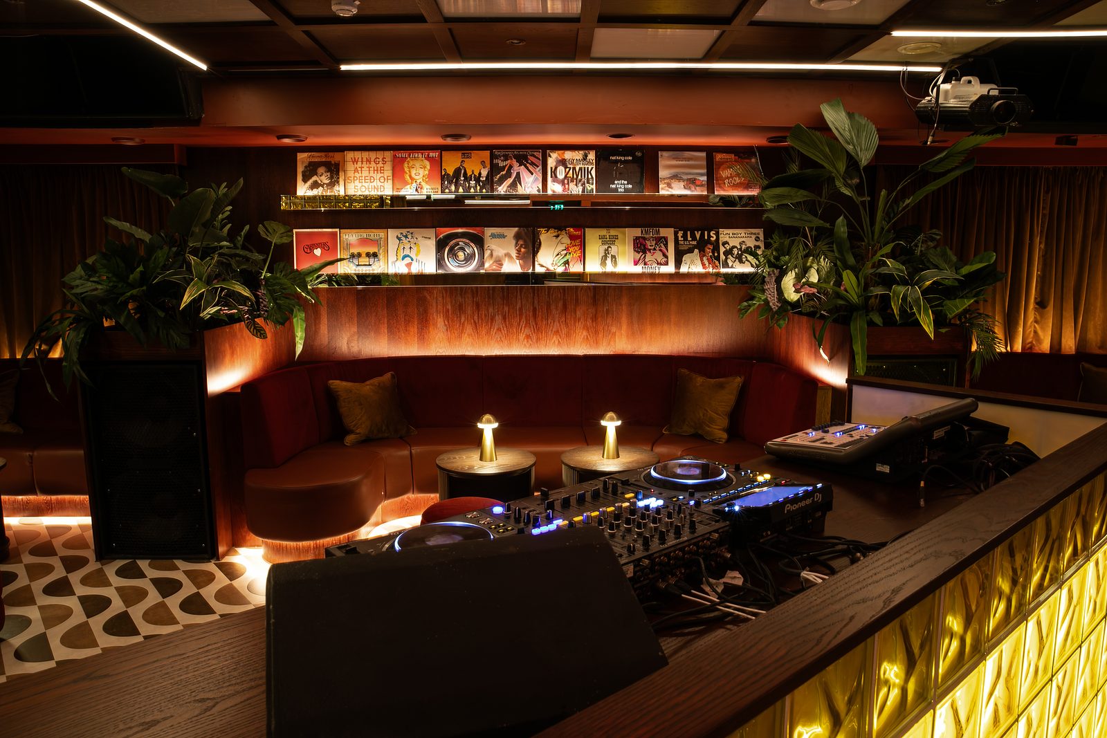 DJ decks in The Vinyl Room at NinetyNine Regent Street, with banquette seating and record sleeves on the shelves behind