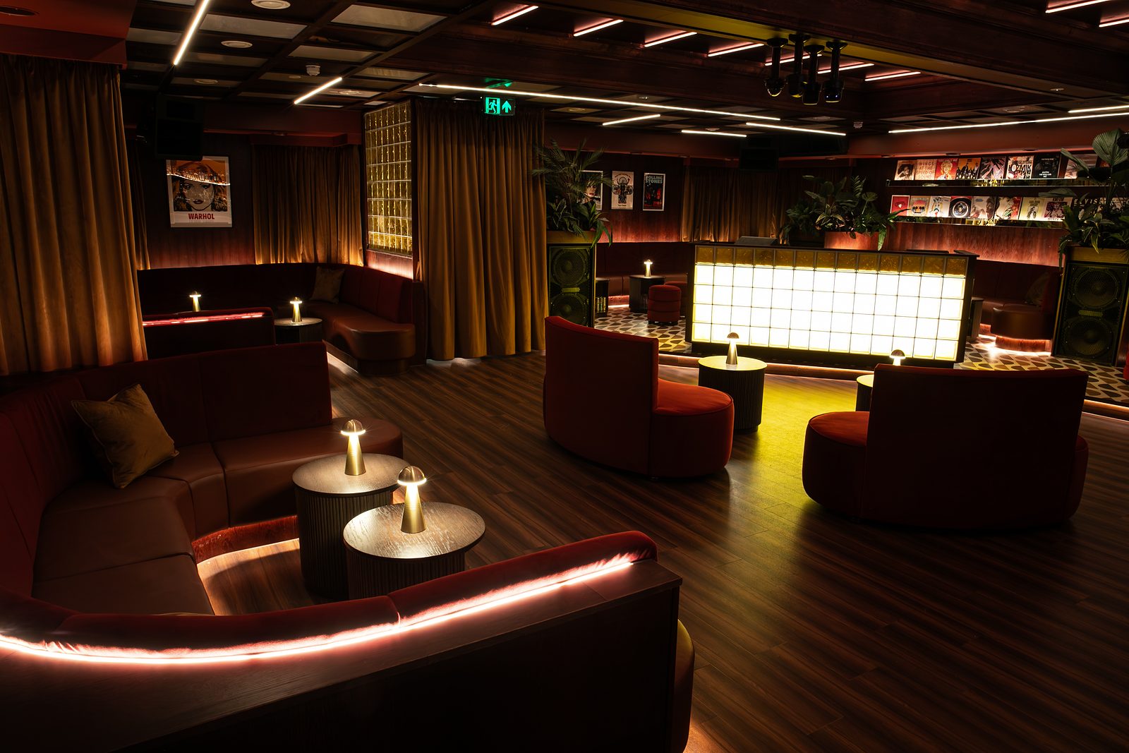 Curved red booths and the illuminated bar in The Vinyl Room at NinetyNine Regent Street