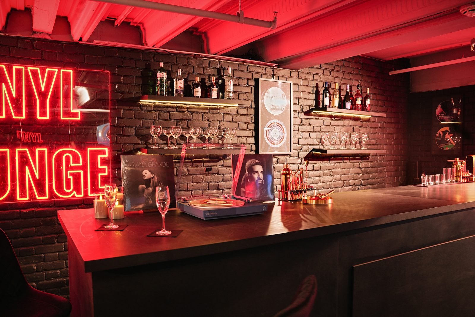 Bar counter with a turntable, album sleeve and glasses beneath the Vinyl Lounge neon at UMusic Shop Camden