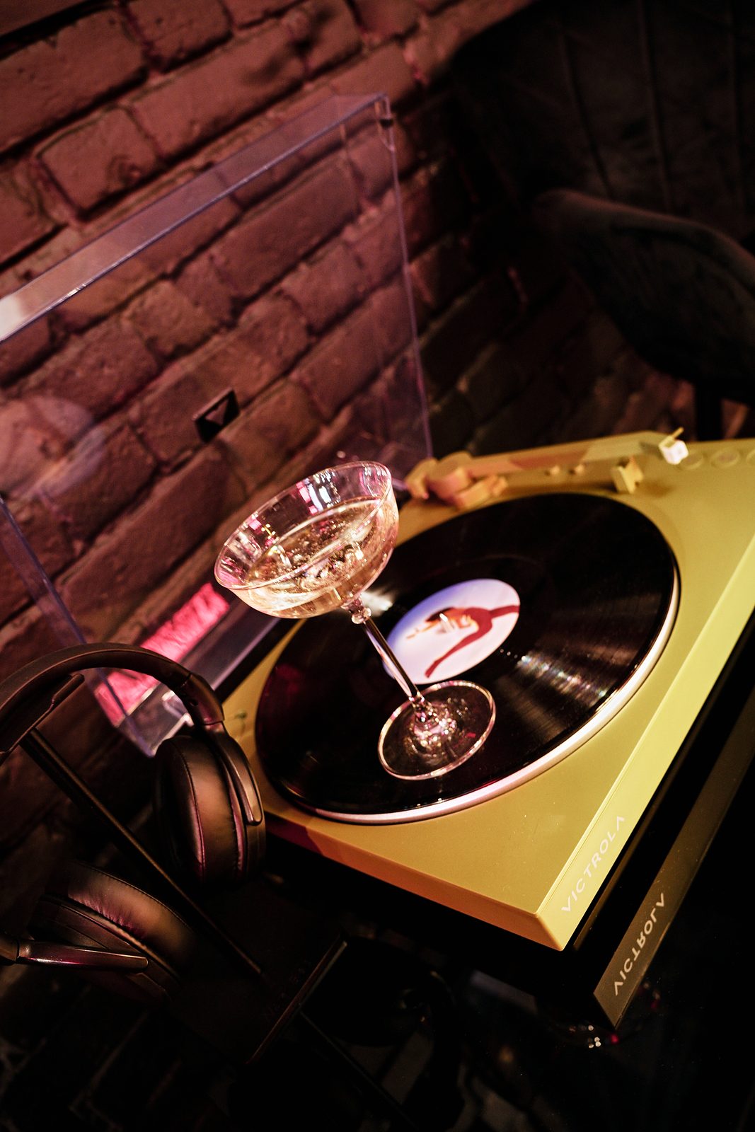 A coupe glass resting on a record on a Victrola turntable at UMusic Shop Camden