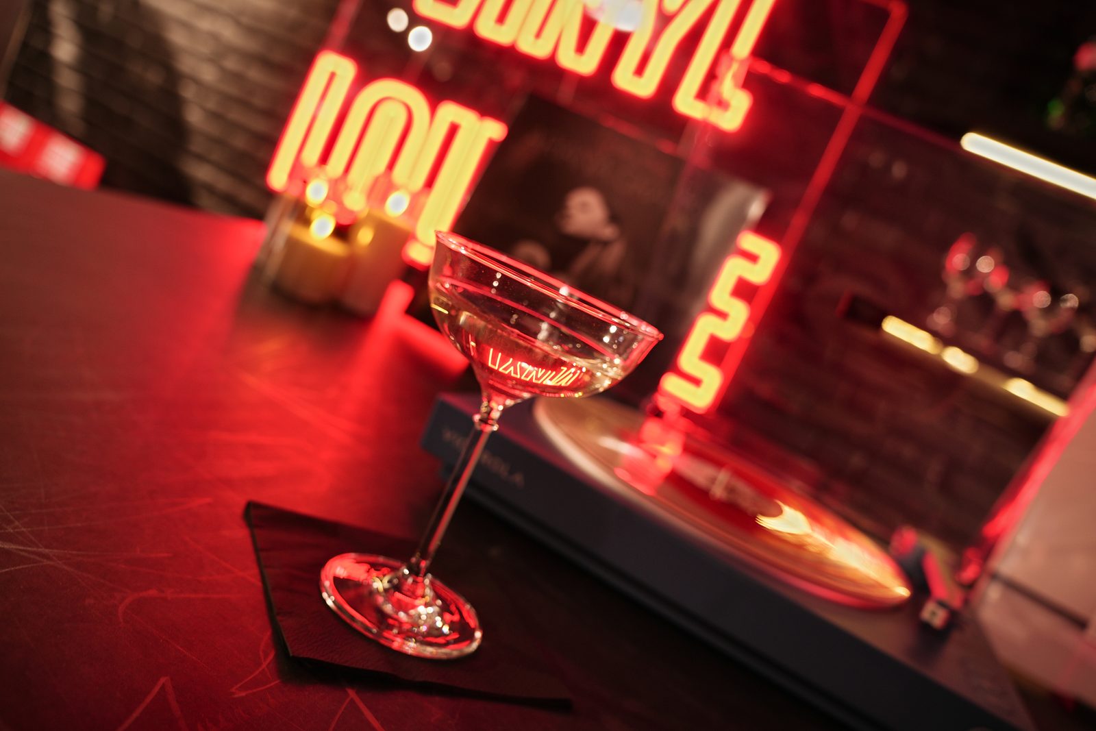 A coupe glass on the bar in front of the Vinyl Lounge neon at UMusic Shop Camden