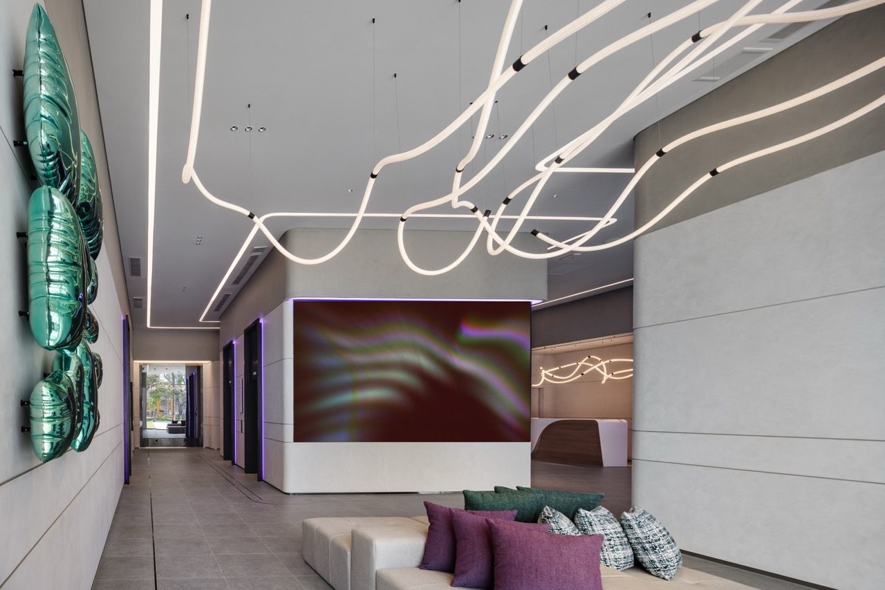 Lobby with a sculptural light installation, green metallic wall art and seating at YOTEL Bangkok Sukhumvit